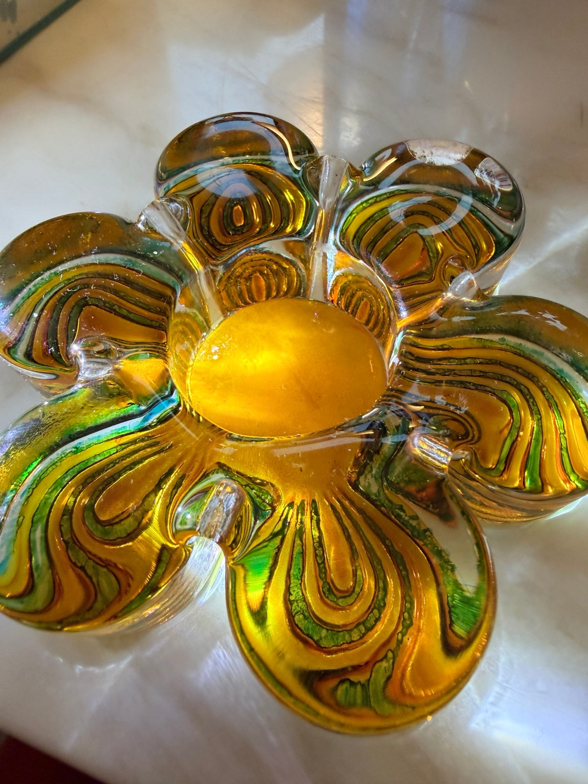 Detalj av kronblad i klart konstglas med guld- och gröna slingor