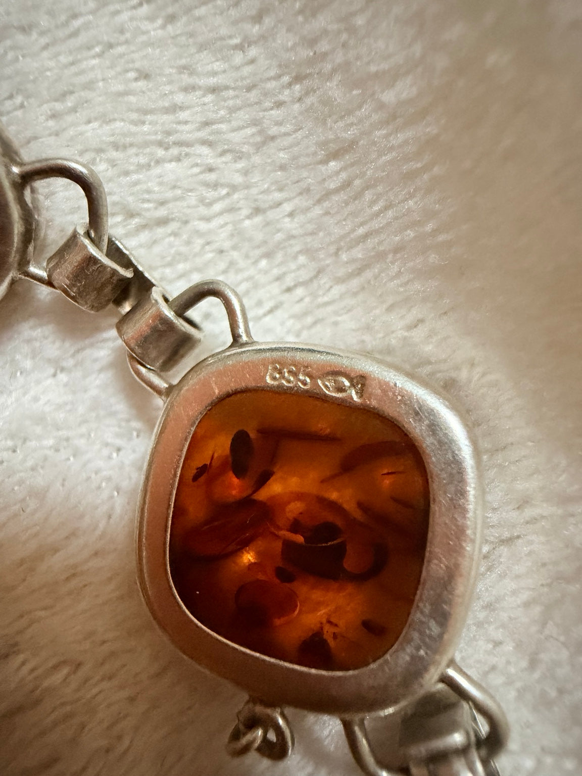 Närbild av stämpel på silverarmband med bärnsten