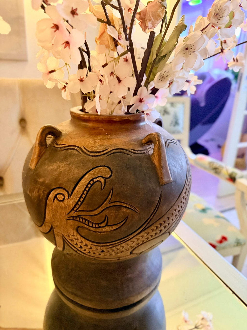 Brun keramikvas med ristad fågeldekor arrangerad med ljusa blommor