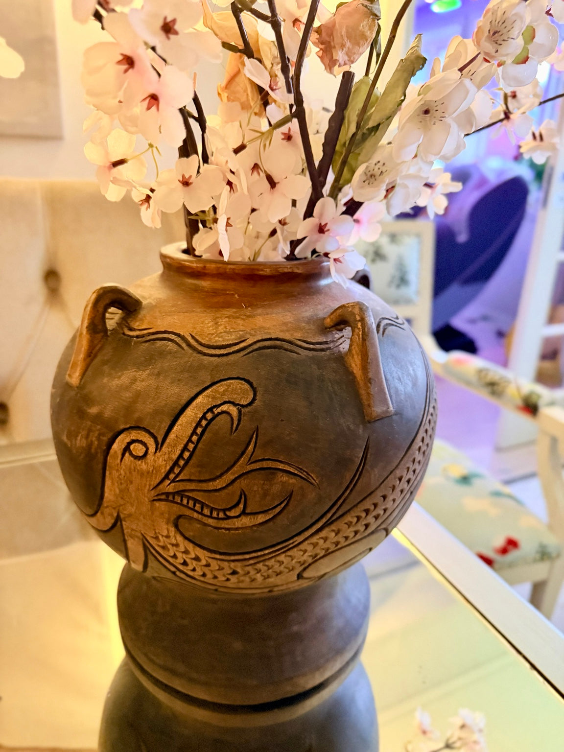 Brun keramikvas med ristad fågeldekor arrangerad med ljusa blommor